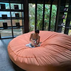 a woman sitting on an orange bean bag chair reading a book in the living room