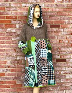 a mannequin wearing a dress made out of patchwork and fabric, standing in front of a brick wall