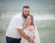 a bride and groom hugging on the beach