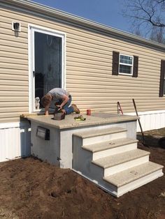 a man working on an outdoor kitchen in front of a house with steps leading up to it