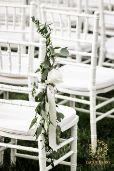 white chairs with flowers and greenery tied to them