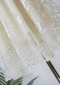 the curtains are hanging in front of a window with white flowers on them and green leaves