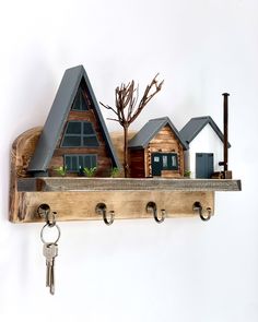 a wooden shelf with some keys hanging from it's sides and houses on top