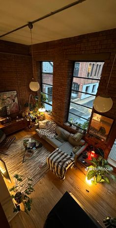 an overhead view of a living room with brick walls and floor to ceiling windows overlooking the city