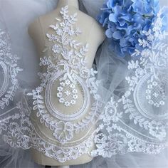 a mannequin with white lace and blue flowers on it