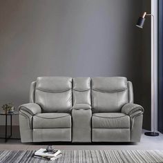 a grey leather reclining sofa sitting on top of a rug next to a lamp