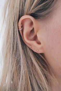 a close up of a person wearing an earring with two small dots on it