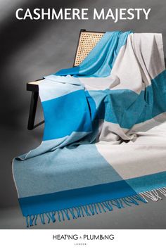 a blue and white blanket sitting on top of a chair next to a gray wall