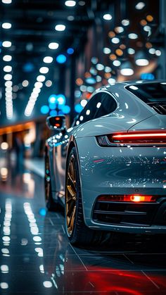 the rear end of a white sports car parked in a parking lot at night time