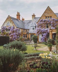 a large house with lots of purple flowers in the front yard