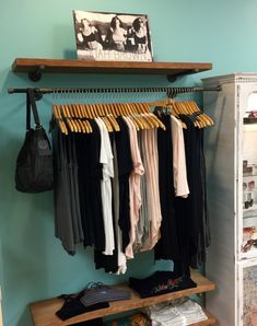 a closet with clothes hanging on the rail and other items sitting on shelves in front of it