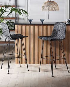 two black bar stools sitting in front of a wooden counter with plants on it