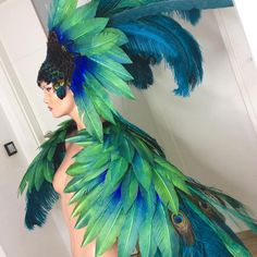 a mannequin dressed in green and blue feathers