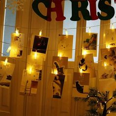 christmas lights strung from the side of a window with pictures on them and candles lit up