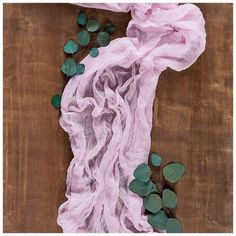 a pink scarf with green leaves laying on it's side next to a wooden table