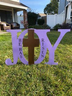 a purple wooden sign with the word jesus on it in front of a white house