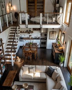 a living room filled with furniture and a stair case next to a dining table on top of a hard wood floor