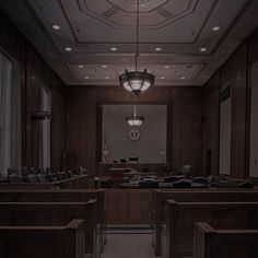 an empty courtroom with wooden benches and lights on the ceiling is seen in this image