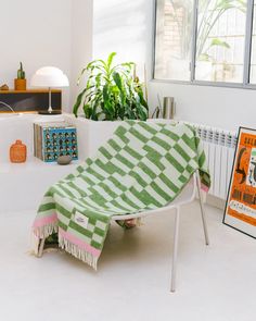 a green and white blanket sitting on top of a chair