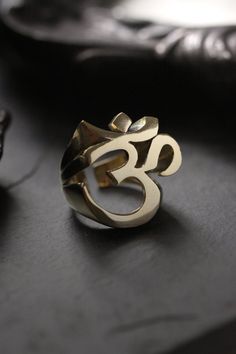 Cool Ohm Sign Ring (version two) original made and designed by Defy Own unique design of Ohm, spiritual meaning of the sacred sound. This version shows detail of the ohm sign in three dimensional. -The ring size is between 7 - 10 US. **Please choose options below.** - The ring dimensions are ; approx. 2.5 x 2.5 x 2.5 cm. **Shipping to World Wide** - Please allow us to prepare the item and parcel between 3-5 working days. For Brass / Silver plated / Gold plated (*Between 5-7 working days For Ster Nickel-free Spiritual Jewelry For Promise, Symbolic Adjustable Ring With Unique Design, Spiritual Ring With Unique Design, Symbolic Rings With Unique Design For Gift, Spiritual Ceremonial Rings With Polished Finish, Symbolic Brass Jewelry For Promise, Adjustable Spiritual Rings, Symbolic Brass Promise Rings, Brass Promise Rings