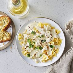 a white plate topped with pasta next to bread