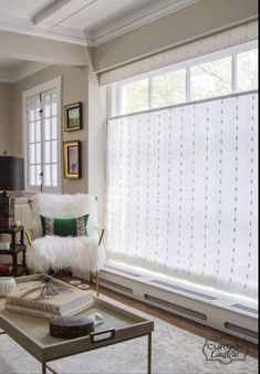 a living room filled with furniture and a large window covered in white blindes next to a coffee table