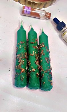 three green candles sitting on top of a table