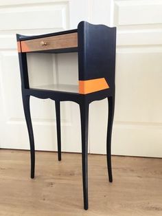 a black and orange table with drawers on it's sides in front of a white door