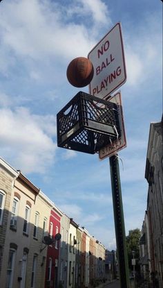 a street sign with a basketball hanging from it's back end in front of some buildings