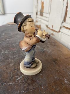 a small figurine of a boy with a pipe on a wooden table in front of a door