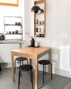 a table and two chairs in a room with a shelf on the wall above it