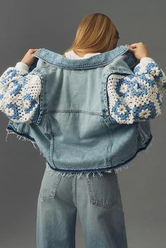 a woman wearing a jean jacket with crocheted flowers on the sleeves and cuffs