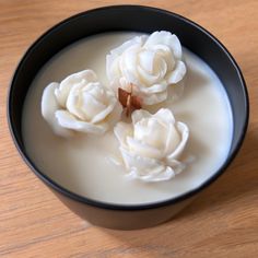 a black bowl filled with white flowers on top of a wooden table