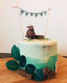 there is a cake that has been decorated with leaves and a bear topper on it