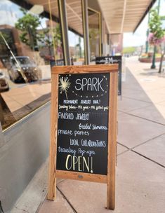 a sign that is sitting on the side of a sidewalk in front of a store