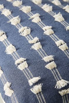 an upholstered blue and white pillow with tassels on the front side