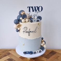 a two tiered cake with blue and white decorations on top is sitting on a wooden table