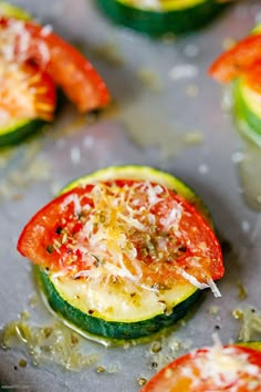 zucchini and tomato halves with cheese on them are ready to be cooked in the oven