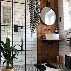 a bathroom with black and white tile, wood paneled walls and a round mirror on the wall