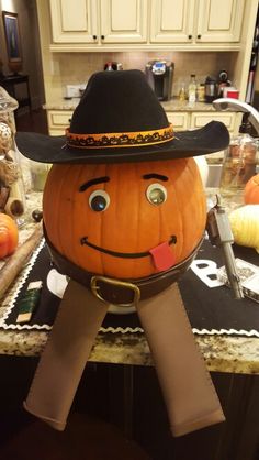 a pumpkin with a cowboy hat on it's head sitting on a kitchen counter