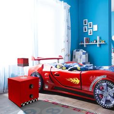 a child's bedroom decorated in blue and red with a sports car bedding