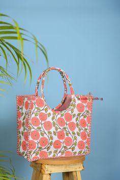 an orange and white bag sitting on top of a wooden stool next to a plant