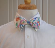 If you are thinking about wedding party orders or matching a bow tie/pocket square/cummerbund to a dress for an event, I offer up to 5 free swatches of fabric to avoid the need for purchases and subsequent returns.  Bow Tie, multicolor floral, pinks, blues, ivory, groom/groomsmen bow tie, bowtie, wedding bow tie, bright pastels An elegant ivory background supports a meadow of bright pastel flowers in shades of pink, turquoise and aqua.  Fresh, summery, elegant - a perfect wedding tie for guests or members of the wedding party. You can't go wrong in this charmer! Also available in an indigo based version - see last photo. The 100% cotton SELF-TIE bow tie has a hook for easy removal that allows the tie to remain intact if you prefer not to tie it every time you wear it. Adjustable using the Summer Wedding Bow Tie With Detachable Bow, Dapper Summer Wedding Bow Tie, Dapper Bow Tie For Spring Weddings, Dapper Spring Bow Tie For Weddings, Detachable Bow For Spring Wedding, White Spring Party Bow Tie, Spring Wedding Bow Ties, Dapper Spring Wedding Bow Tie, Fitted Multicolor Bow Tie For Gift