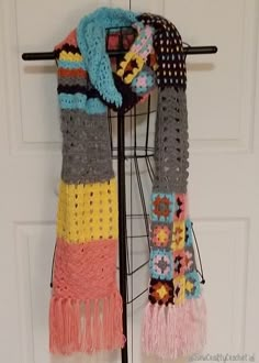 a multicolored crocheted scarf hanging on a door