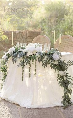 a table with flowers and greenery is set up for an outdoor wedding reception in the sun