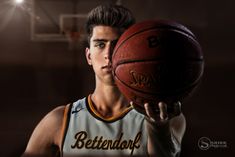 a young man holding a basketball in his right hand and looking at the camera with an intense look on his face