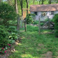 a small house in the middle of some trees and bushes, with a gate leading to it