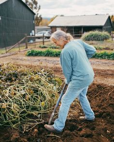 an older woman digging in the dirt with a shovel