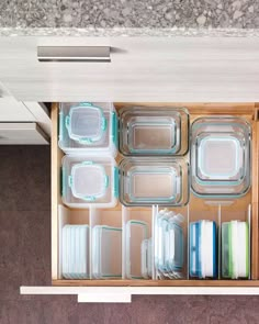 an open drawer filled with glass containers on top of a counter