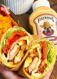 a person holding a sandwich with meat and lettuce next to french fries on a table